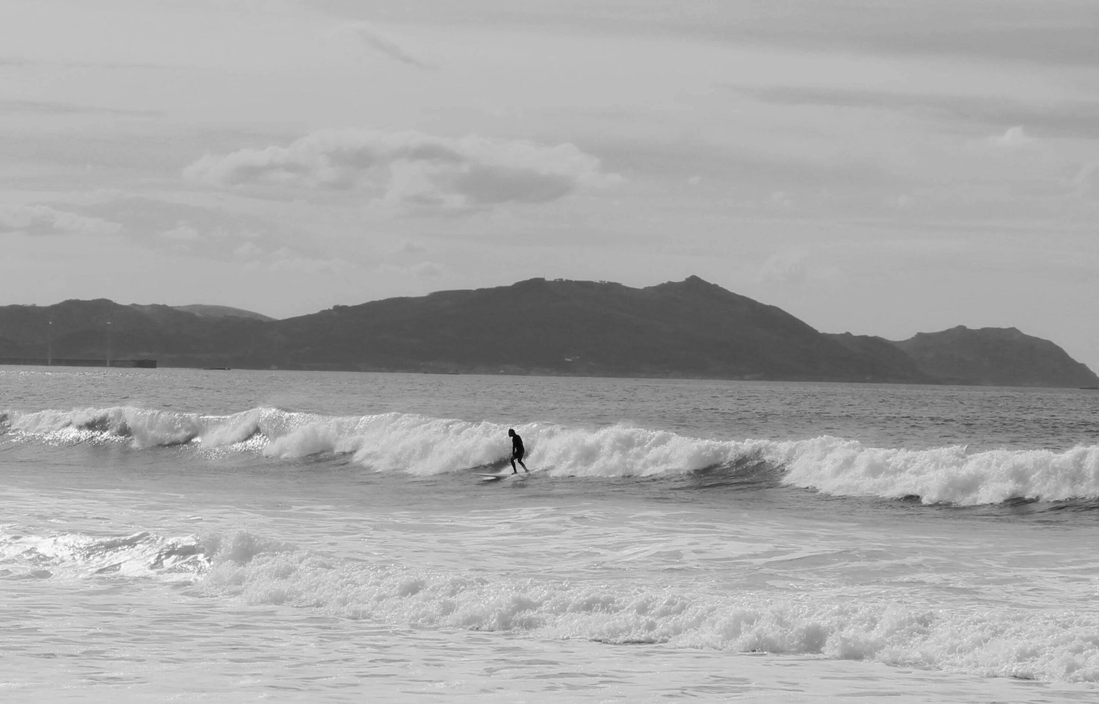 Lonely surfer riding waves in stormy sea